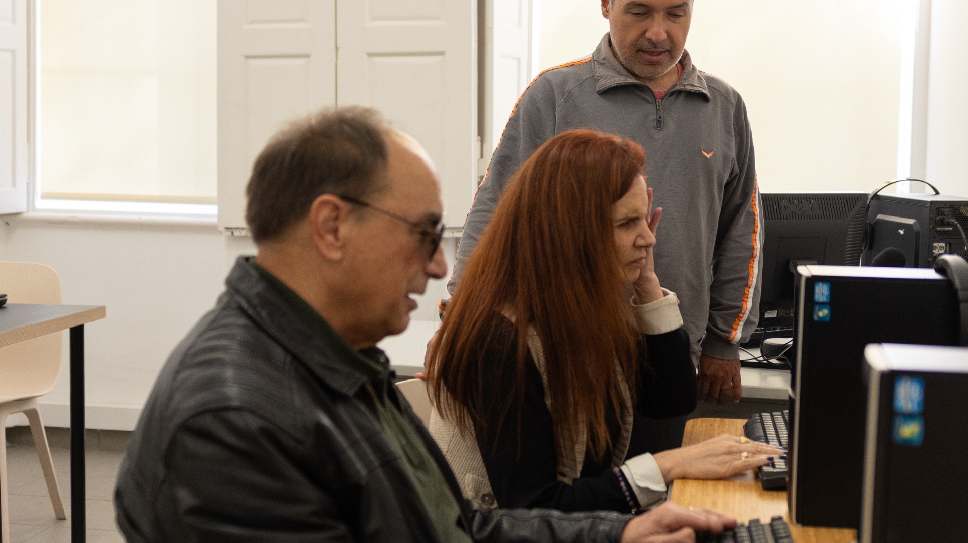 Fotografia do professor de informática da APEC a lecionar uma formação a dois beneficiários, na sala de informática