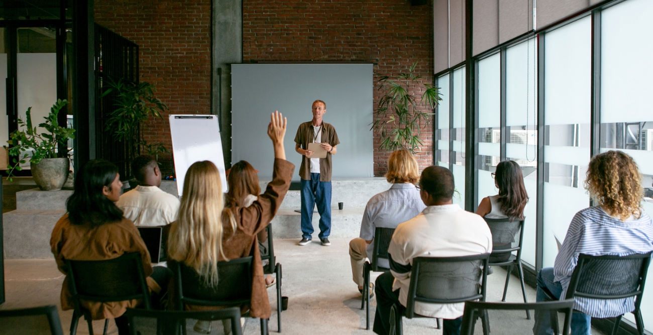Formador a apresentar uma sessão de formação a um grupo de participantes numa sala de aula, representando os cursos de formação online promovidos pela Associação Promotora do Ensino dos Cegos.
