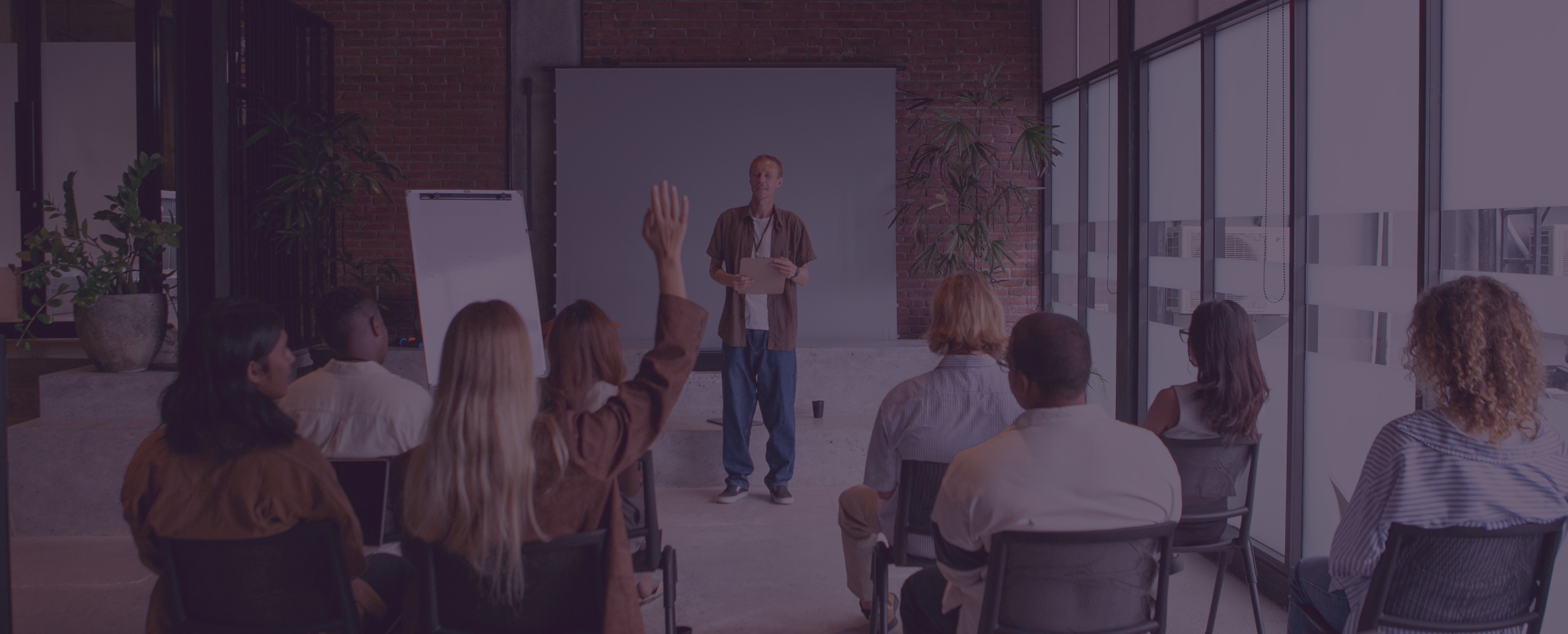 Formador a apresentar uma sessão de formação a um grupo de participantes numa sala de aula, representando os cursos de formação online promovidos pela Associação Promotora do Ensino dos Cegos.